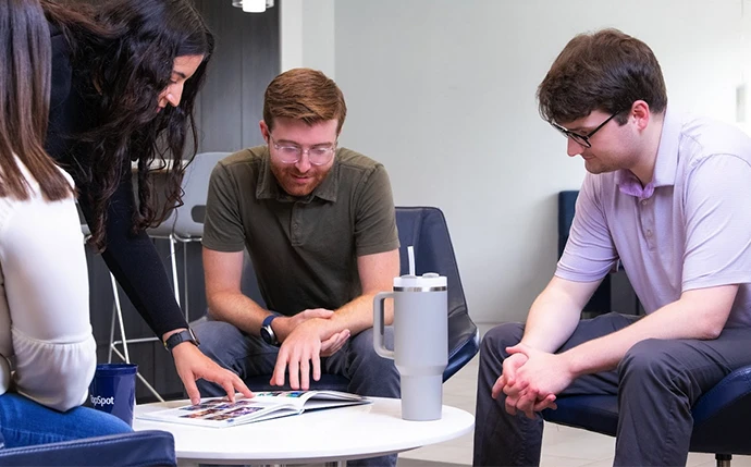 Four people at a table reviewing ecommerce web development services.