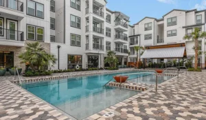 The Aero on 24th apartment community courtyard with the resort-style pool and the white multifamily building behind it