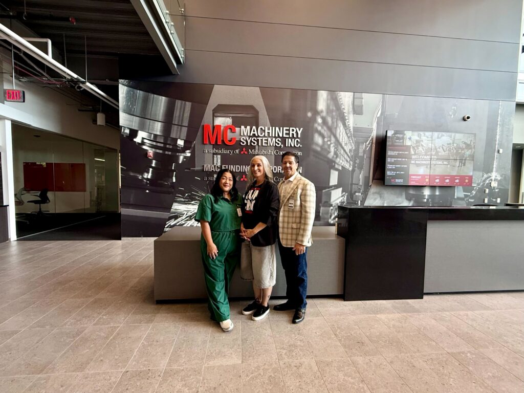 Three people stand in the Machinery Systems showroom lobby during an OuterBox client visit.