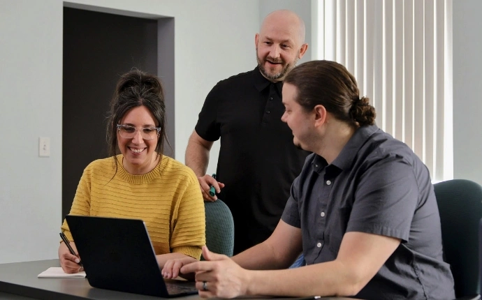 OuterBox team reviewing website design for manufacturers around a laptop