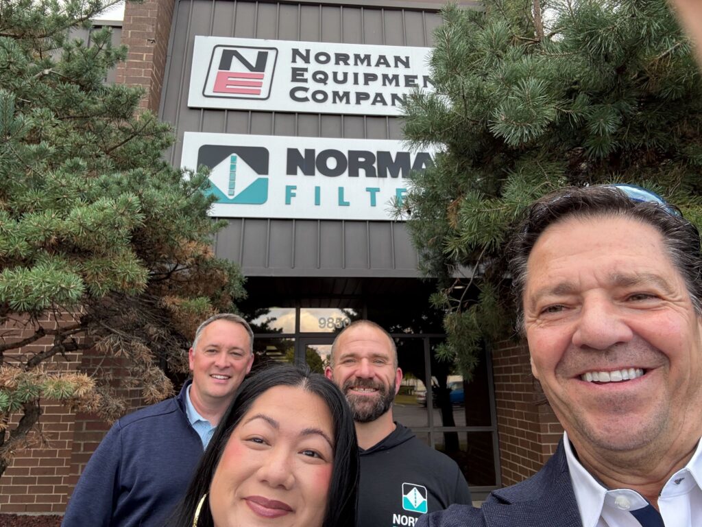 Group selfie outside the Norman Equipment Company and Norman Filters building during an OuterBox client visit.