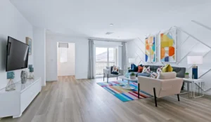 A bright Touchstone Living model-home living room with light wood flooring, a colorful striped rug, and modern abstract wall art