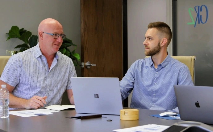 Two OuterBox team members discussing direct primary care marketing performance during a laptop-based planning meeting