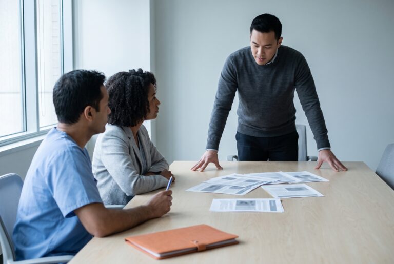 A strategist walks two clinical leaders through a printed performance review.