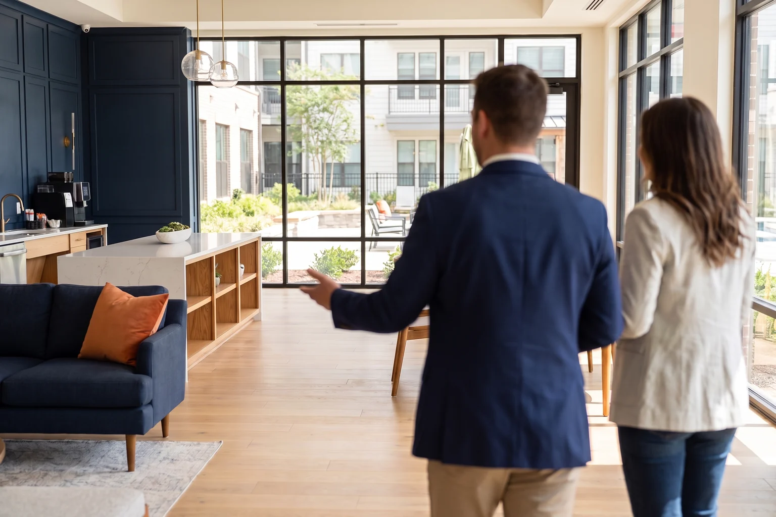 A leasing agent and a prospective resident touring a bright apartment community clubhouse