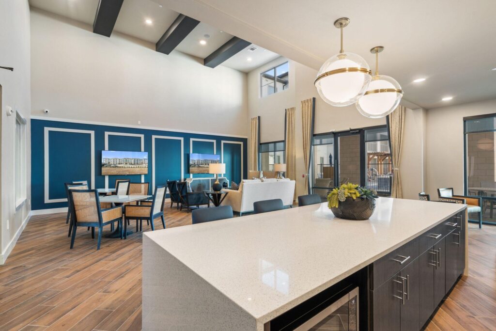 Parmore Arcadia Trails senior-living clubhouse interior with open kitchen island, dining and lounge area, navy accent wall and pendant lighting